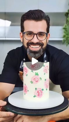 a man holding a cake with roses on it and smiling at the camera while wearing glasses