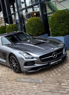 a silver mercedes sports car parked in front of a building