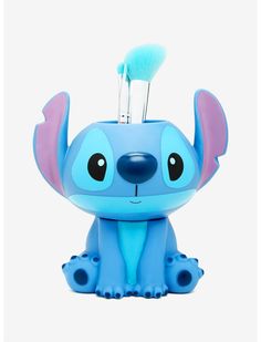 a small blue toy with a toothbrush in it's mouth and ears, sitting on the ground