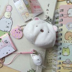 a white stuffed animal keychain sitting on top of a notebook next to other items