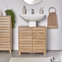 a white sink sitting on top of a wooden dresser next to a mirror and towel dispenser