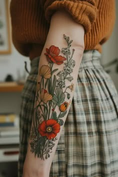 a woman's arm with flowers on it and an orange flower in the middle