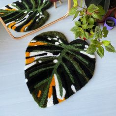 a heart shaped rug sitting on top of a white table next to a mirror and potted plant