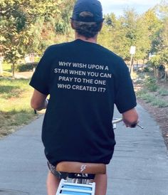 a man riding a skateboard down a sidewalk while wearing a t - shirt that says, why wish upon a star when you can pray to the one who created it?