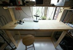 the desk is made out of plywood and has two stools in front of it