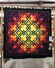 a colorful quilt hanging from a rack in a store