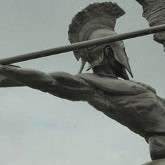 a statue of a man with a bird on his head is shown in front of a cloudy sky