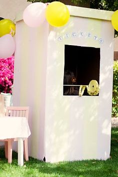 a white outhouse with balloons and decorations on the lawn in front of it,