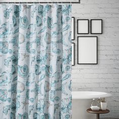 a shower curtain with shells on it next to a white bath tub and wooden floor