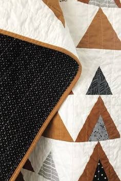 a black and white quilt on top of a bed next to a brown and white pillow