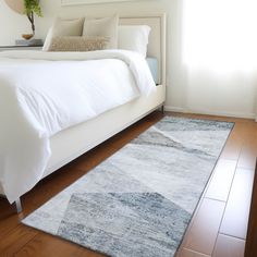 a large white bed sitting on top of a hard wood floor next to a window