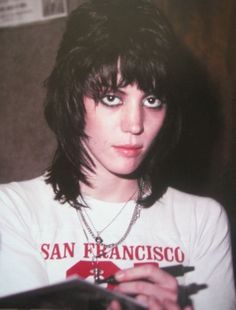 a woman with black hair wearing a white shirt and holding a clipboard in her hands