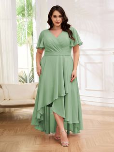 a woman in a green dress posing for the camera with her hands on her hips