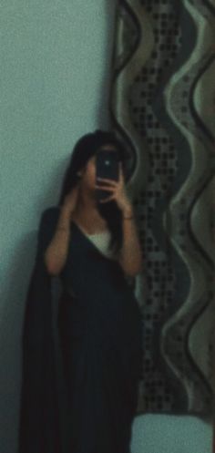 a woman taking a selfie in front of a mirror with her cell phone up to her face