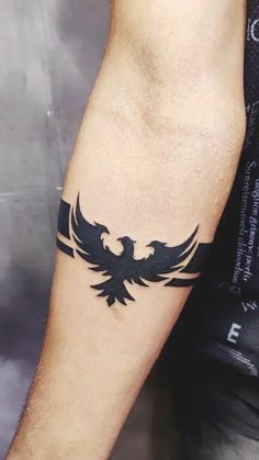 a man's arm with a black bird tattoo on it