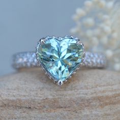 This Heart Aquamarine Engagement Ring is part of our Adeline Collection which is characterized by a gorgeous, genuine gemstone held in place atop a filigree basket. Diamonds stud the hidden halo and filigree, and sparkle down the triple half eternity shank.

Center Stone: Genuine AAA Blue Aquamarine, 10mm Heart Cut, averaging 3 carats.
Side Stones: 93 Diamonds – you choose Lab Grown or Organic – averaging F-G, VS2-SI1 and 0.49 total carats.

All shapes, sizes and gemstones available upon request Exquisite Heart Cut Gemstone Jewelry, Heirloom Heart Cut Gemstone Jewelry, Heart Cut Moissanite Gemstone Jewelry, Aquamarine Halo Setting Jewelry For Anniversary, Aquamarine Halo Jewelry For Anniversary, Anniversary Aquamarine Halo Jewelry, Anniversary Jewelry With Aquamarine Halo Setting, Fine Jewelry Aquamarine Gemstones For Wedding, Heart Cut Blue Topaz Wedding Jewelry