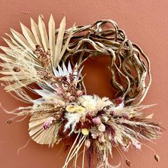 a dried wreath hanging on the side of a pink wall next to a brown door