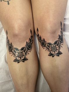 two women with tattoos on their legs are laying in bed and one has her leg crossed