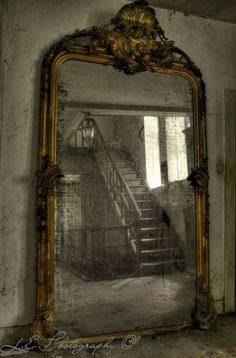 an old fashioned mirror with stairs in the middle and a window on the other side