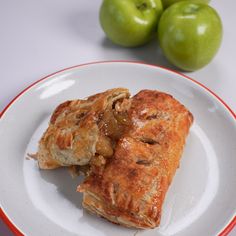 two pieces of food on a plate next to some green apples