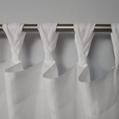 four white curtains hanging on a metal rod