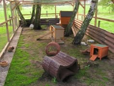 an outdoor chicken coop in the middle of a grassy area with trees and other animals