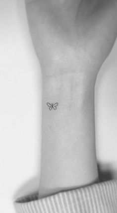 a woman's wrist with a small butterfly tattoo on the left side of her arm