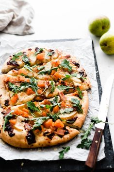 a pizza sitting on top of a piece of paper next to an apple and knife