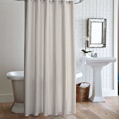 a white shower curtain in a bathroom next to a sink and tub with a mirror