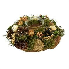 an arrangement of pine cones, flowers and moss with a glass bowl in the center