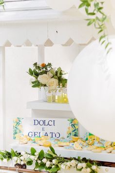 a table topped with lots of white flowers and plates filled with cake next to balloons