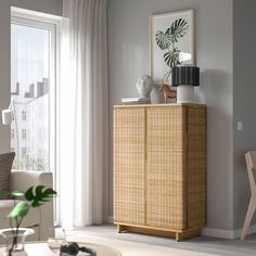 a living room with a wicker cabinet in the corner and a potted plant on top