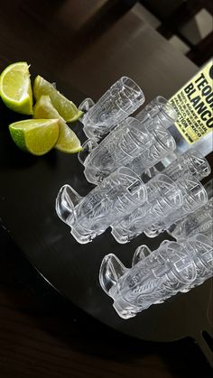 four glasses sitting on top of a table next to lemons and lime wedges