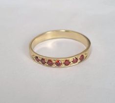 Romantic half eternity garnet ring, dainty stacked gemstone ring, Feminine minimalist jewelry for women, available in high quality 14k gold plating, sterling silver, 9k solid yellow gold, or 14k solid yellow, rose, or white gold.    This handmade band is delicate and elegant. The ring is set with 7 beautiful deep red garnets, January's birthstone.  It is available in nickel-free 14k gold plating over brass or over silver, sterling silver, 9k solid yellow gold, or 14k solid yellow, rose, or white gold.    This beautiful ring is subtle yet striking and sits elegantly on the finger. It will look amazing when stacked with other rings but can also be an impressive stand-alone item.  It can also be a great engagement ring.  Get this classic ring to add chic to your everyday look. Item details: 1 Garnet Eternity Ring, Dainty Stackable Ruby Ring For Anniversary, Dainty Stackable Ruby Ring For Promise, Garnet Stackable Promise Rings, Garnet Gold Ring, Silver Garnet Ring, Feminine Minimalist, Garnet Ring Silver, Romantic Jewelry