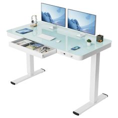 two computer monitors sitting on top of a white desk next to each other with magazines underneath them