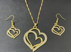 Set Of 3 Beautiful Double Hollow Hearts Jewelry Set With gold color Pendant Necklace, Pendant Earrings And Chain Bracelet With Sparkling Zirconia Vintage Style Jewelry Collection Valentine's Day Gold Jewelry Sets, Gold Jewelry Sets For Valentine's Day Party, Valentine's Day Gold Jewelry Gift Set, Yellow Gold Metal Jewelry Sets For Gift, Gold Heart-shaped Jewelry Sets For Party, Heart-shaped Gold Jewelry Sets For Parties, Valentine's Day Metal Jewelry Set Gift, Gold Heart Pendant Jewelry Set For Anniversary, Gold Jewelry Sets For Valentine's Day