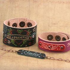 two leather bracelets with buttons on them and a chain attached to the wristband