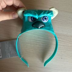 a hand holding a blue headband with an angry face on it