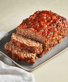 a loaf of meatloaf on a metal tray with a white towel next to it