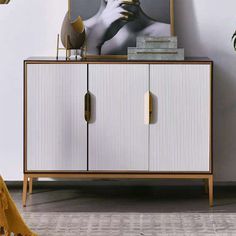 a white and gold cabinet with a painting on it next to a potted plant