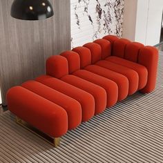 a red couch sitting on top of a wooden floor next to a black light fixture