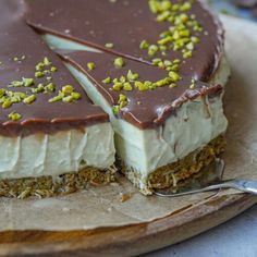 a chocolate and white cake with pistachio toppings on a wooden platter