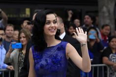 a woman in a blue dress waves to the crowd