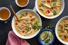 three bowls filled with soup next to cups and spoons