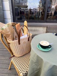 there is a basket with bread on the table next to a cup and saucer