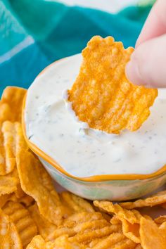 a person dipping cheese into a bowl of chips