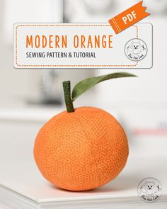 an orange sitting on top of a white table next to a book with the title modern orange sewing pattern and video