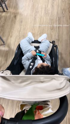 a baby in a stroller is playing with his toy car seat and looking at the camera