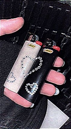 a person holding two lighters in their left hand and an electronic device in the other