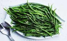 a white plate topped with green beans on top of a table next to a fork